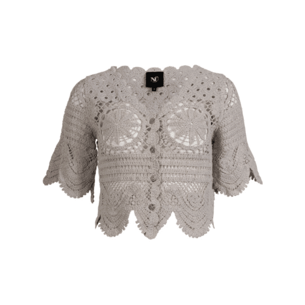 Ziona strik cardigan fra Nü. Denne strikkede cardigan er hæklet i et dekorativt mønster med fine, håndlavede detaljer. Den har korte ærmer, knaplukning foran og en bølget kant forneden og ved ærmerne, som giver et feminint og vintageinspireret udtryk. Det åbne hulmønster gør den ideel som let lag over en top eller kjole.