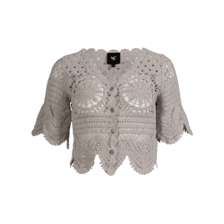 Ziona strik cardigan fra Nü. Denne strikkede cardigan er hæklet i et dekorativt mønster med fine, håndlavede detaljer. Den har korte ærmer, knaplukning foran og en bølget kant forneden og ved ærmerne, som giver et feminint og vintageinspireret udtryk. Det åbne hulmønster gør den ideel som let lag over en top eller kjole.