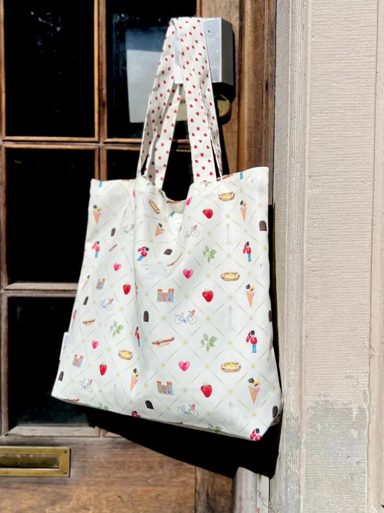 Totebag i canvas med danske akvarelmotiver – Praktisk og smuk Opdag vores unikke totebag i slidstærkt canvas polyester, dekoreret med smukke akvarelmotiver, der hylder det bedste ved Danmark. Tasken er designet med små, charmerende danske ikoner – perfekt som minde fra Danmark eller som en personlig favorit i hverdagen. Denne totebag er ikke bare stilfuld, men også utrolig funktionel og alsidig. Brug den som strandtaske, shoppingtaske eller indkøbsnet – den rummelige størrelse gør det nemt at have både badetøj, dagligvarer eller dine vigtigste ejendele med på farten. Med både lange og korte hanke kan tasken bæres over skulderen eller i hånden, hvilket giver maksimal komfort og fleksibilitet – uanset om du er på ferie, på arbejde eller ude at handle. Derfor vil du elske denne totebag: Fremstillet i holdbar canvas polyester Udsmykket med unikke, originale danske akvarelmotiver Perfekt som souvenir eller gaveidé Ideel til både turister og danskere Rummelig og praktisk til indkøb, shopping eller strandture Udstyret med både lange og korte hanke for nem bæring Tilføj et strejf af dansk charme til din hverdag – eller giv en betænksom gave, der fortæller en historie om Danmark. Motiv: Danish Mål: 48 cm bred 50 cm høj Kvalitet: 100% Canvas Polyester Vaskeanvisning: Kan vaskes ved 30 grader i maskine. Brug pletfjerner hvis nødvendigt. Tørrer fladt.